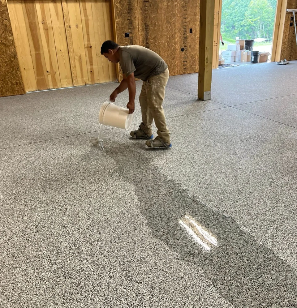 Crew pouring clear topcoat over a flake floor