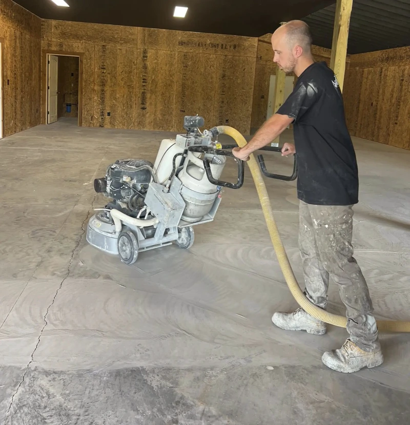 Crew member running a diamond grinder across a concrete floor